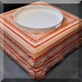 F57. Slip-covered orange and white ottoman. 